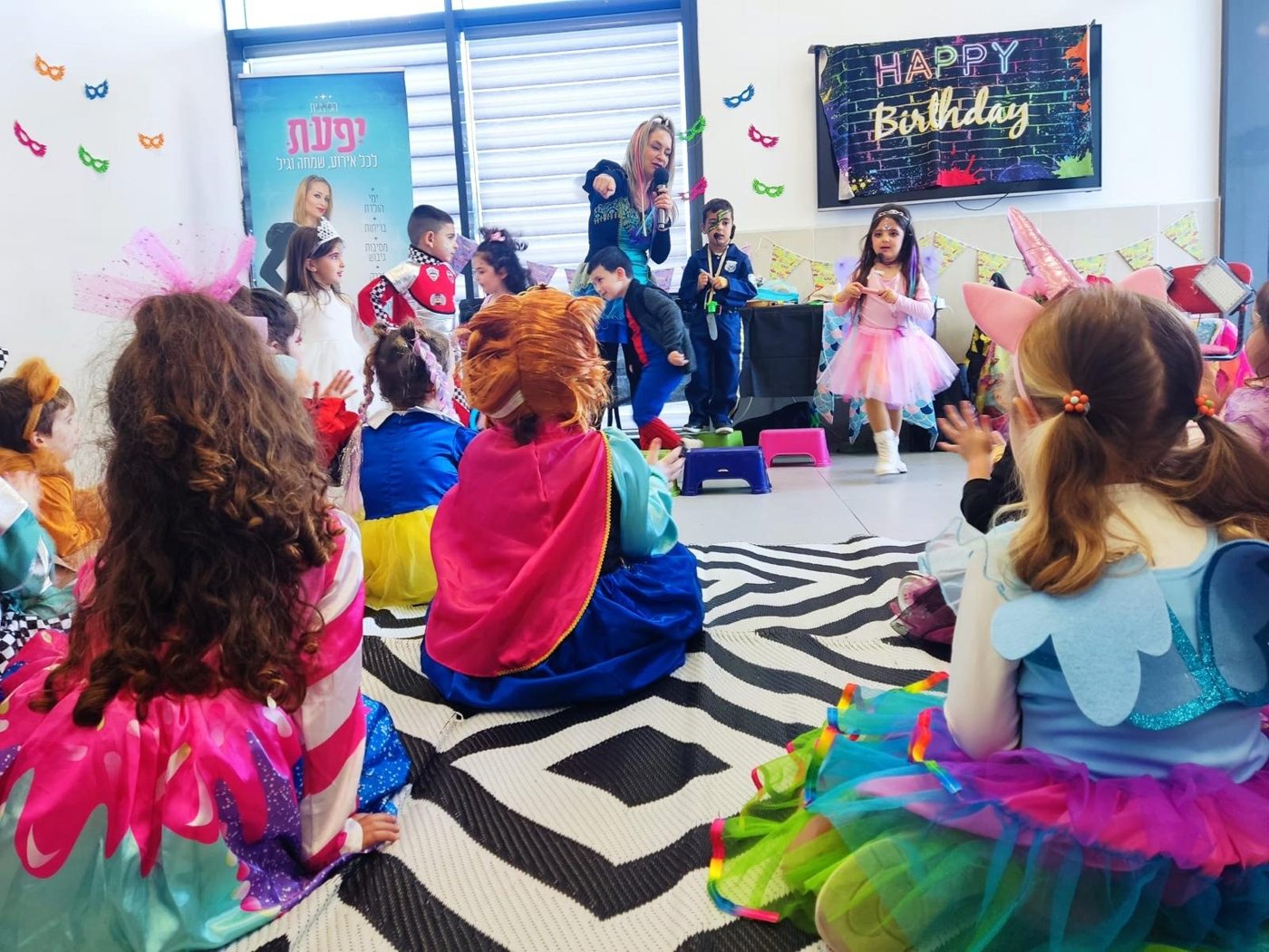 ילדים יושבים במעגל וצופים בהפעלה, מקצה לקצה של החדר